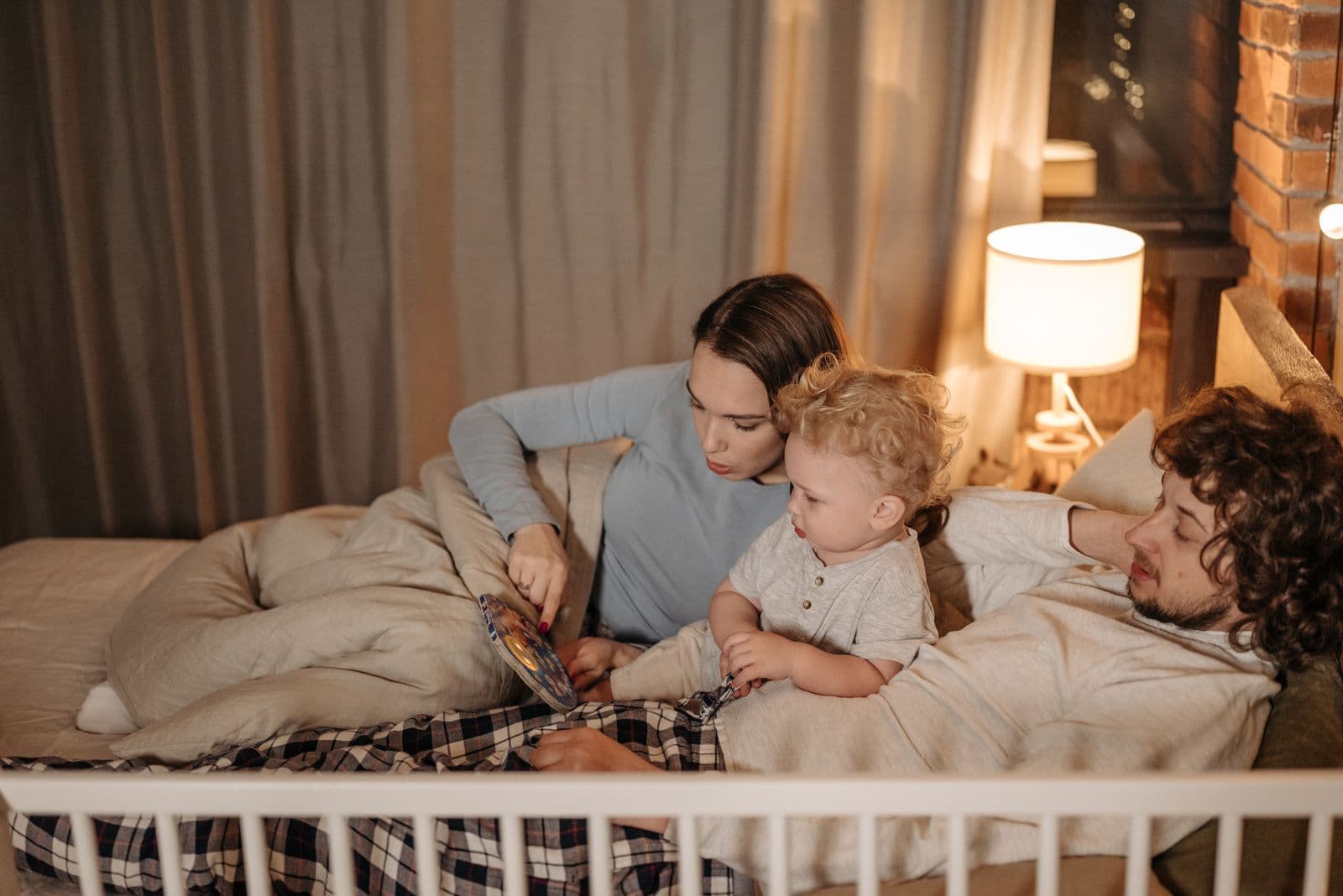 Parents reading a story with their child in bed