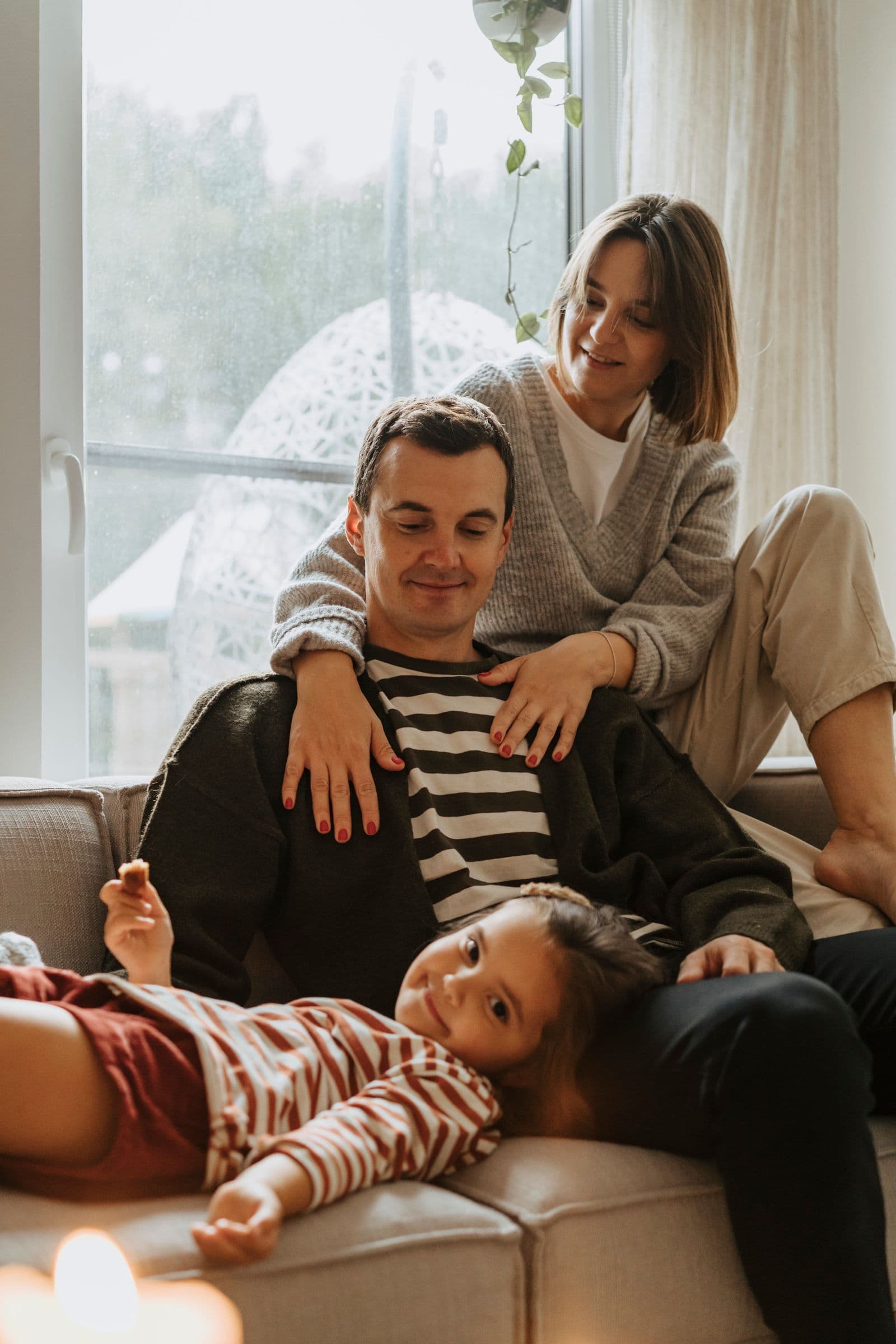 Parents laughing with their daughter on the couch